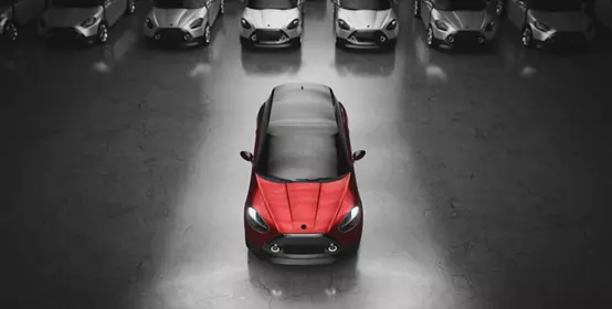 Single red car parked in front of a fleet of gray cars