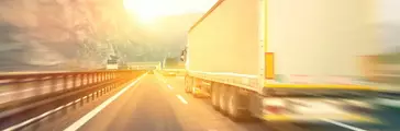 Generic semi trucks speeding on the highway at sunset with motion blur.