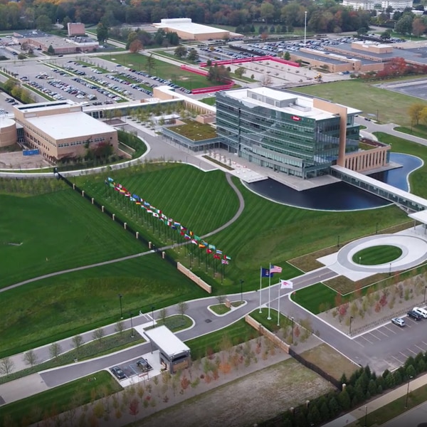 A birds eye view of a Dow facility surrounded by parking lots, grassy fields, and a cluster of flags