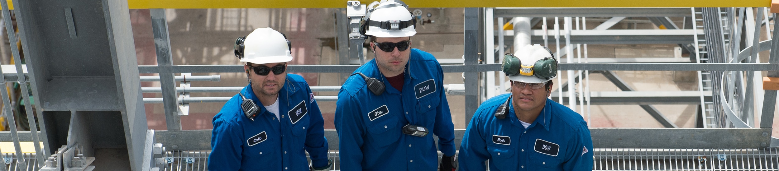Three Dow plant workers look at the camera from a walkway